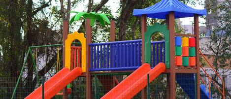 A playground with slides, climbing structures, and a playhouse.