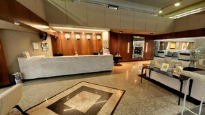 Un hall de hotel con mostrador de recepción, zona de estar y una escalera.