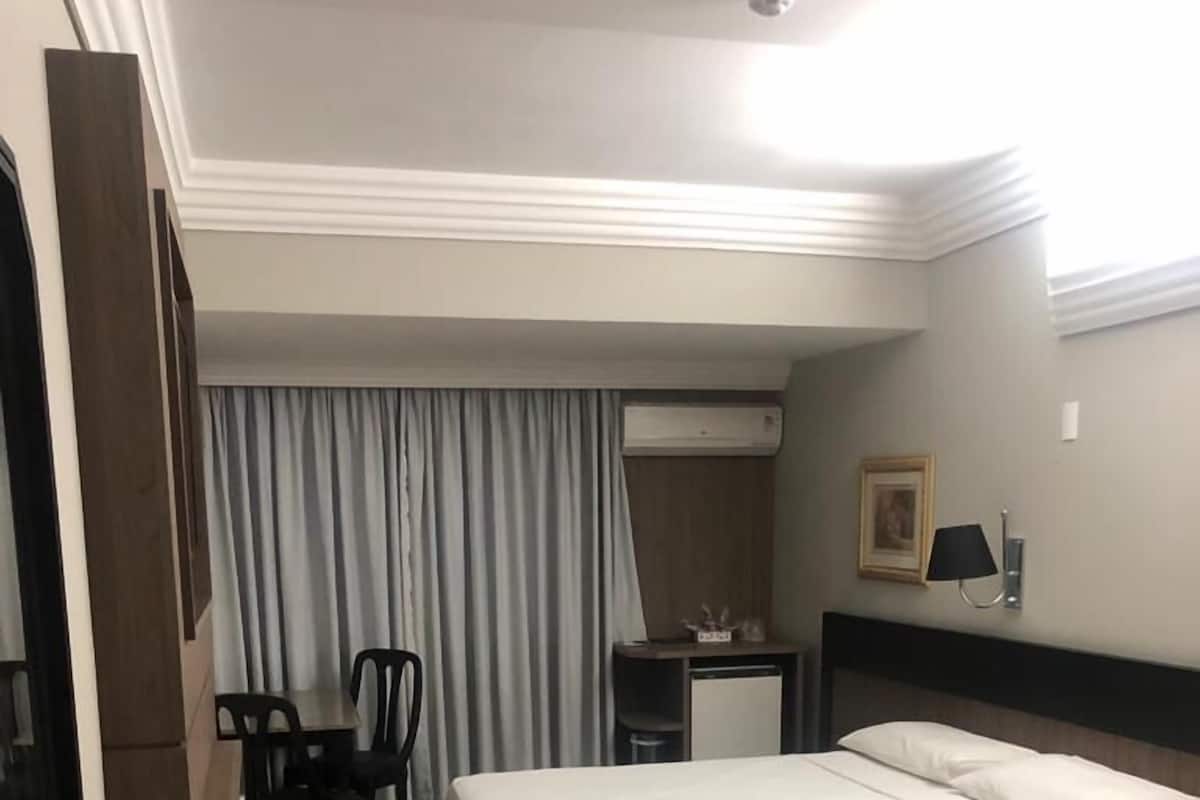 Ein Hotelzimmer mit einem Bett, einem Schreibtisch, einem Stuhl und einem kleinen Tisch.