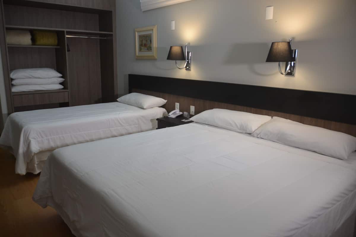 Ein Hotelzimmer mit zwei Betten, einem Kleiderschrank und zwei Wandleuchten.