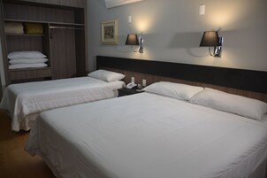 Habitación de hotel con dos camas, un armario y dos lámparas fijadas a la pared.