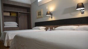 Habitación de hotel con dos camas, un armario y lámparas fijadas a la pared.