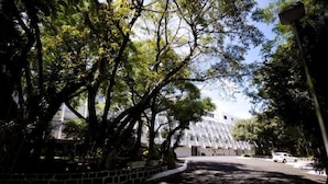 Un edificio de estilo arquitectónico moderno, rodeado de árboles y un área pavimentada.
