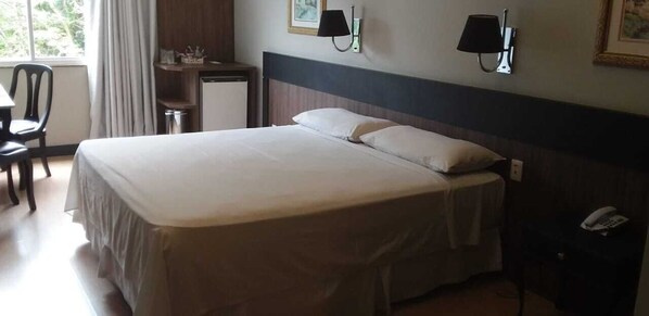 Una habitación de hotel con una cama grande, un escritorio, una silla y un teléfono.