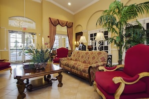 A spacious lobby with a red sofa, a wooden coffee table, and a large potted plant. - 3BD 2BA Condo Sleeps 8 Gold RVC30963 Bedroom RHOF (Orlando)