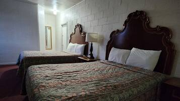 Quarto de hotel com duas camas, um espelho, uma luminária e parede com padrão de tijolos.