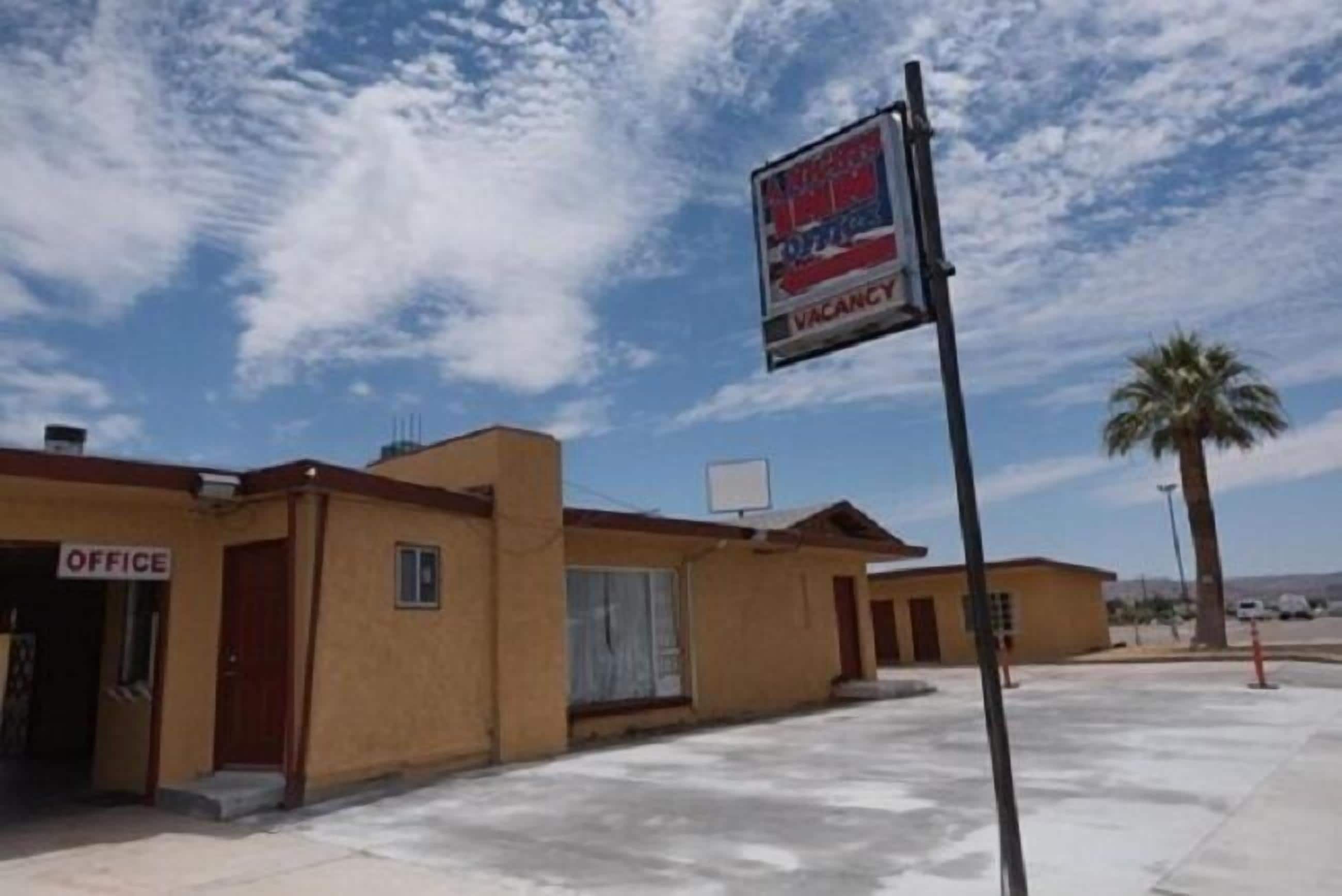 A building with an 'OFFICE' sign, a 'VACANCY' sign, and a clear sky.