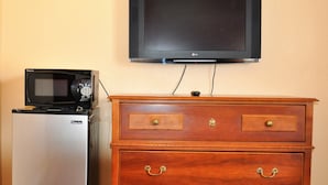 Een kitchenette met een magnetron en een wandgemonteerde flatscreen televisie.