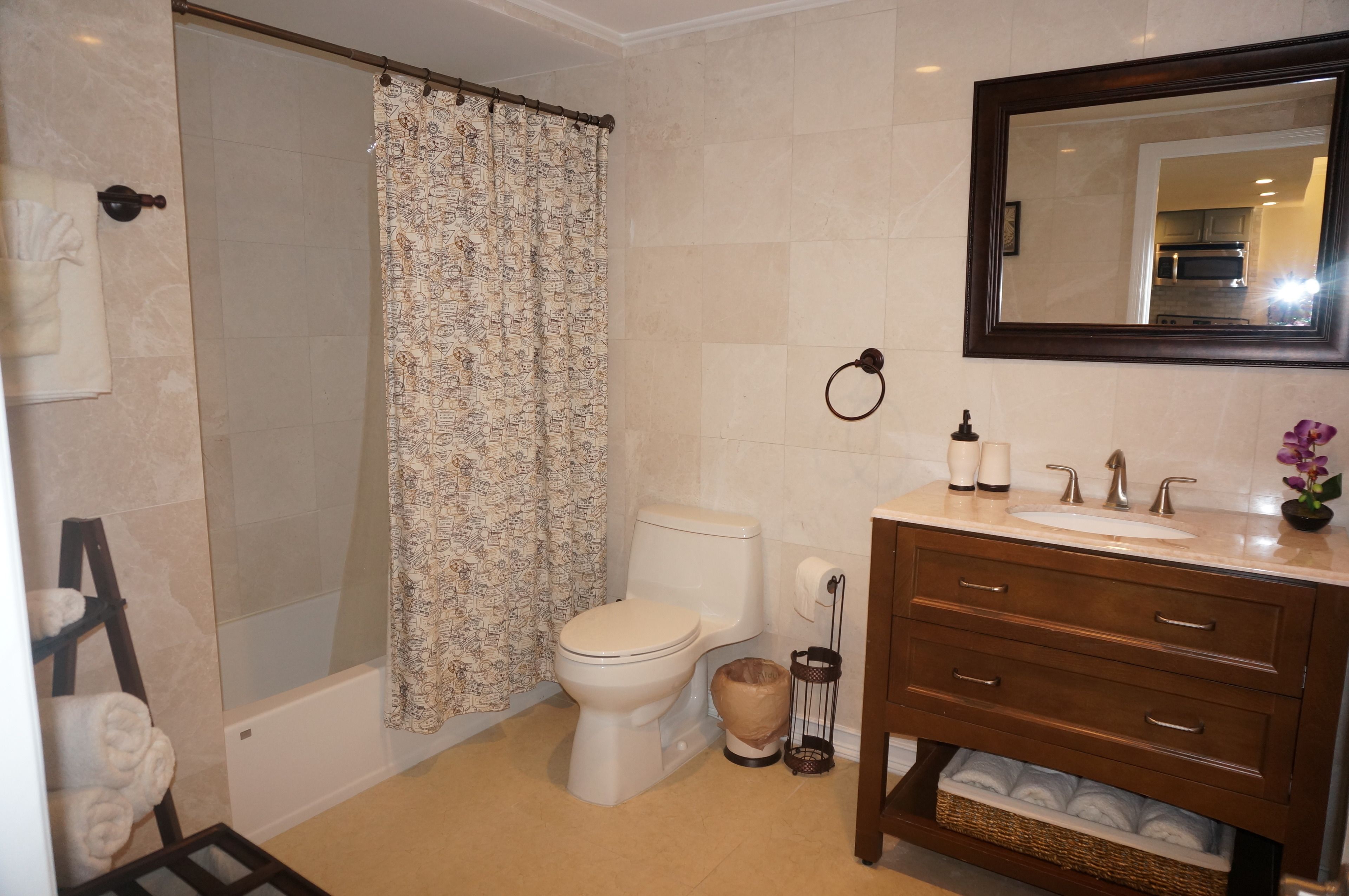 Un baño con ducha, inodoro y tocador con lavabo y espejo.