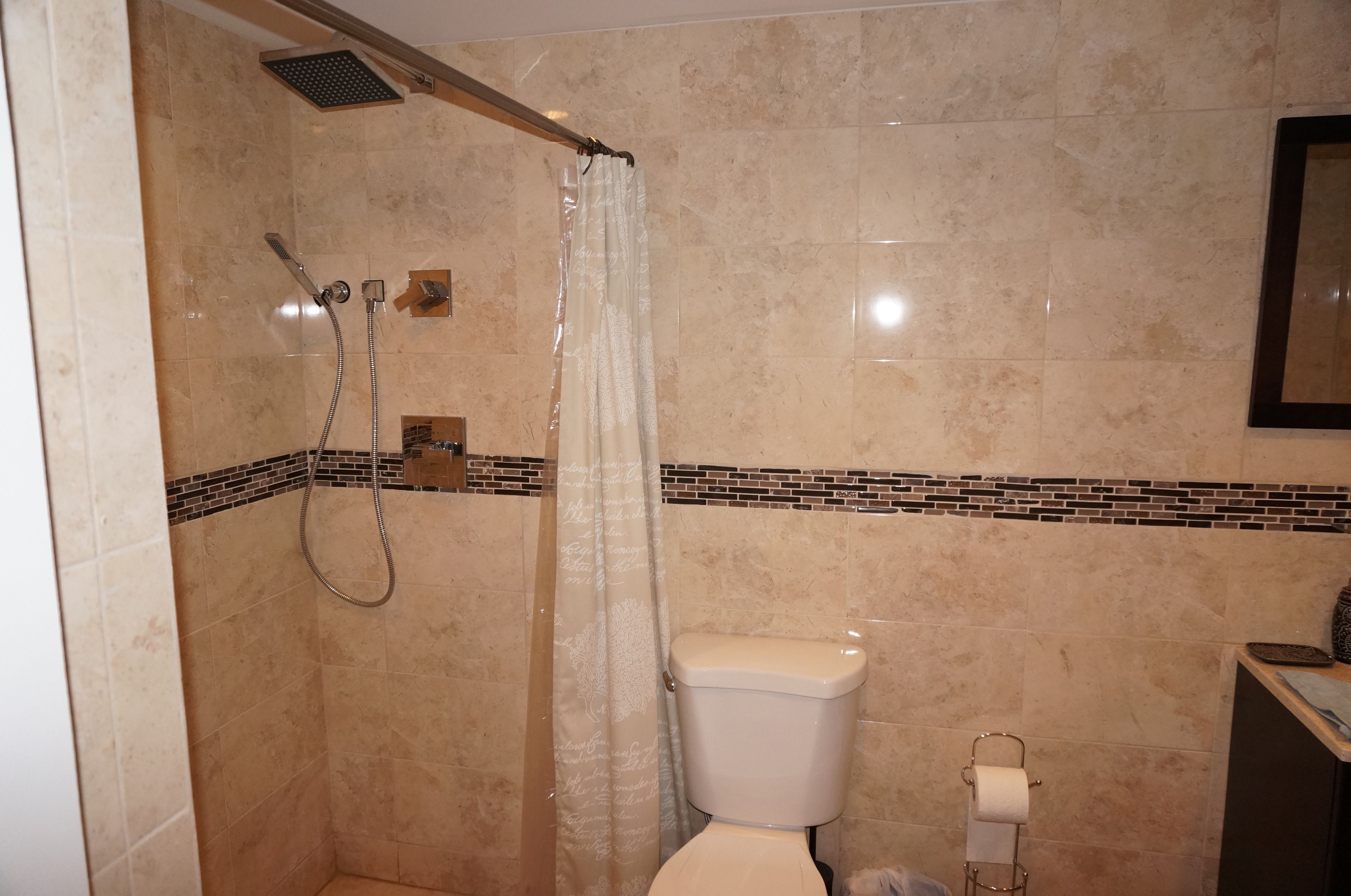 A bathroom with a shower, toilet, and a towel rack.