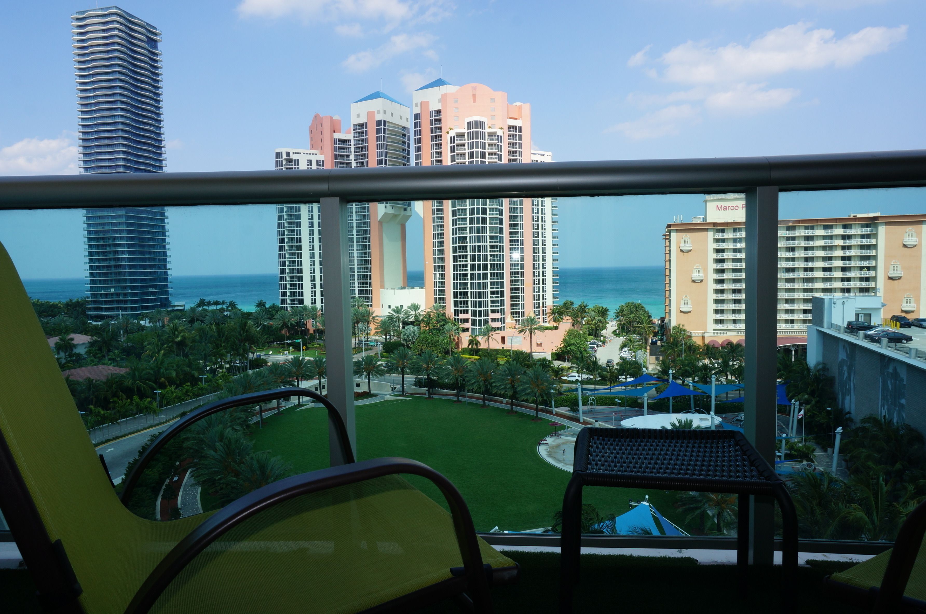 A balcony with a view of a cityscape, including tall buildings and a green park area.