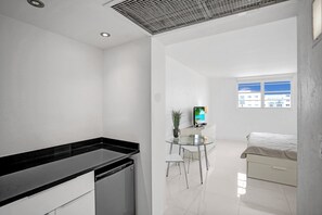 Une chambre à coucher moderne et minimaliste, avec un lit, une petite table de chevet et un téléviseur.