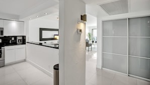 A modern kitchen with white cabinetry, a black countertop, and a stainless steel range hood. - Ocean Reserve Condominium (Sunny Isles Beach)