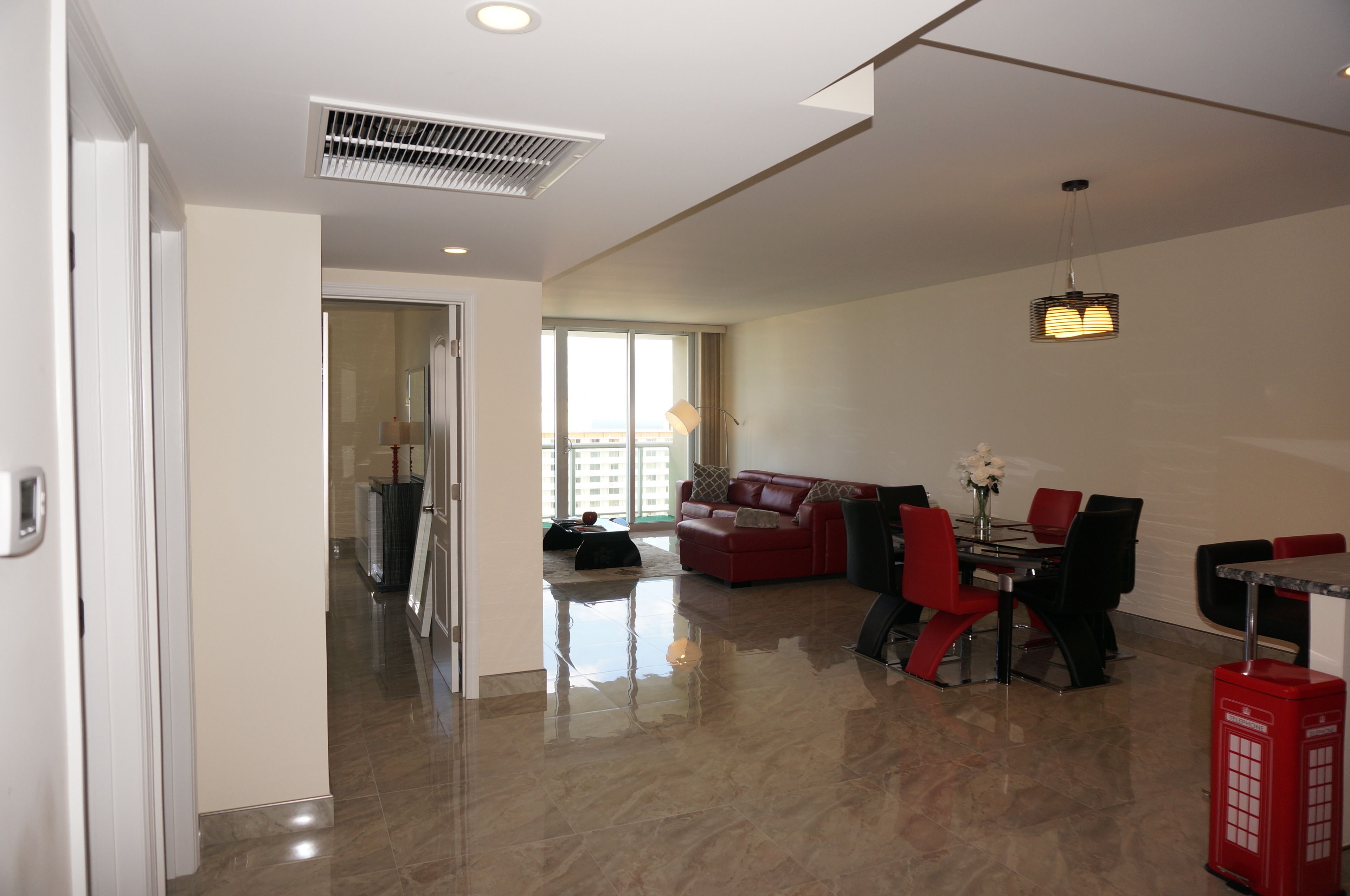 A spacious living area with a red sofa, a dining table with chairs, and a red telephone booth.