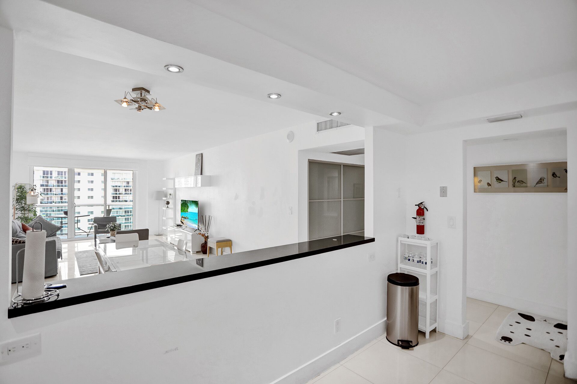 A modern kitchen with a black countertop, white cabinets, and a stainless steel trash can.
