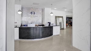 A reception desk with a logo, a computer, and a mirror. - Ocean Reserve Condominium (Sunny Isles Beach)
