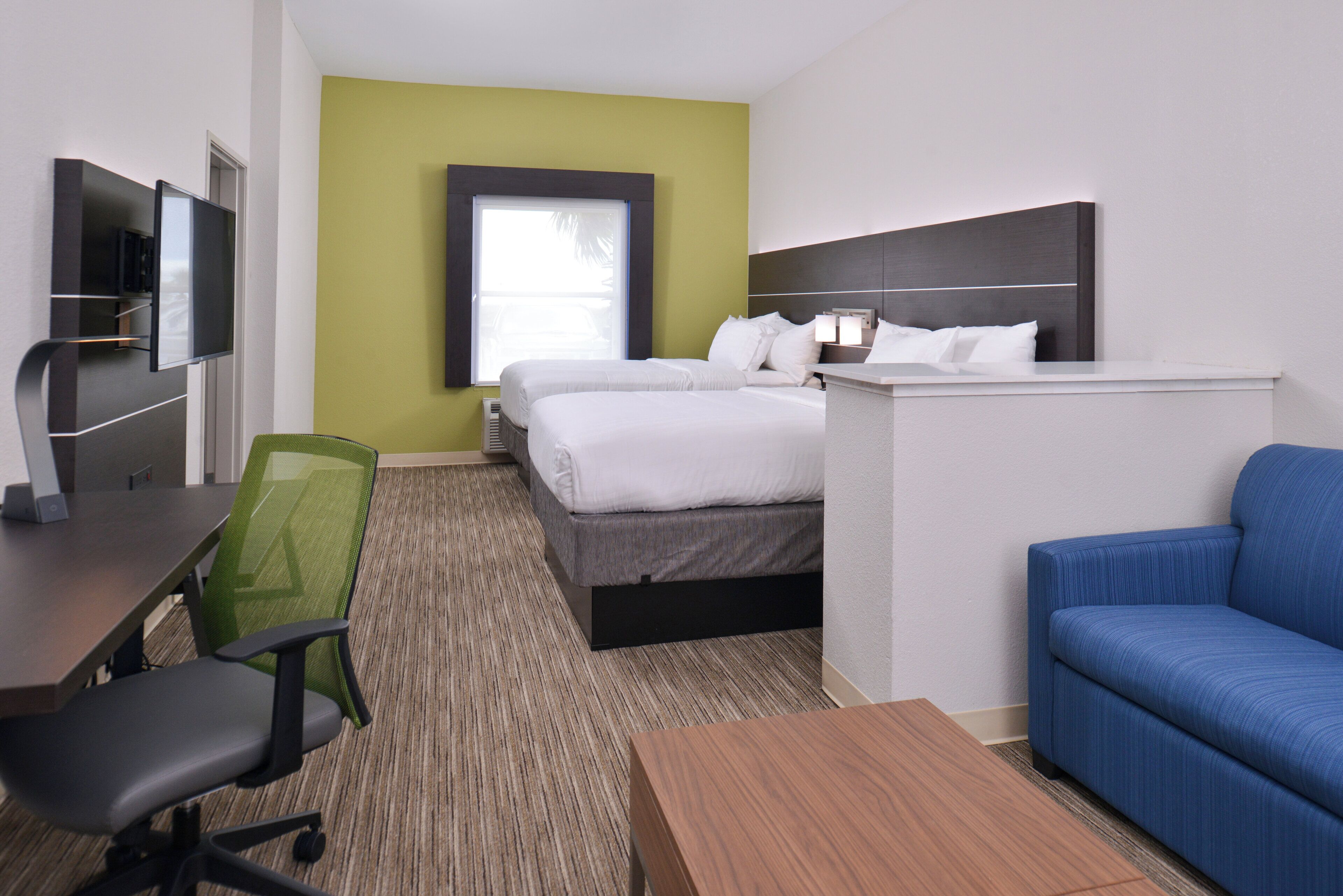 Une chambre d’hôtel avec un lit, un bureau, une chaise, un canapé et une télévision.