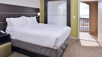A hotel room with a bed, bedside table, and a view of the outside.
