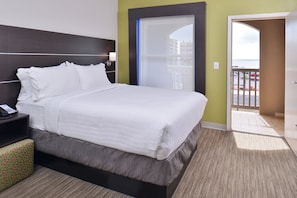 A hotel room with a bed, bedside table, and a view of the outside.