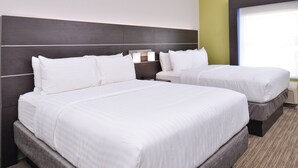Une chambre d’hôtel avec deux lits, une tête de lit sombre et une grande fenêtre.