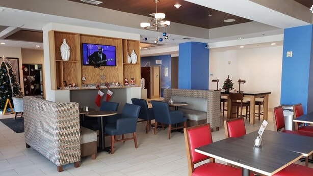Een modern restaurant met een houten bar, blauwe en rode zitplaatsen en een kerstboom.