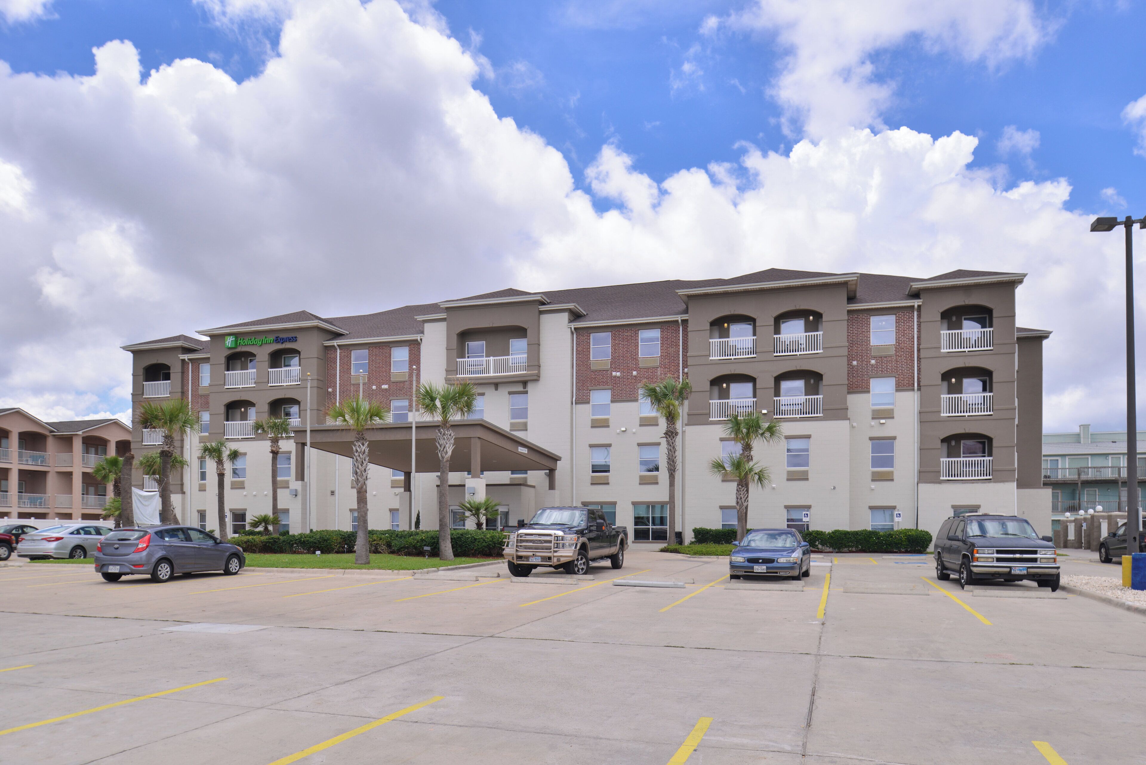 A multi-story hotel with a parking lot in front.