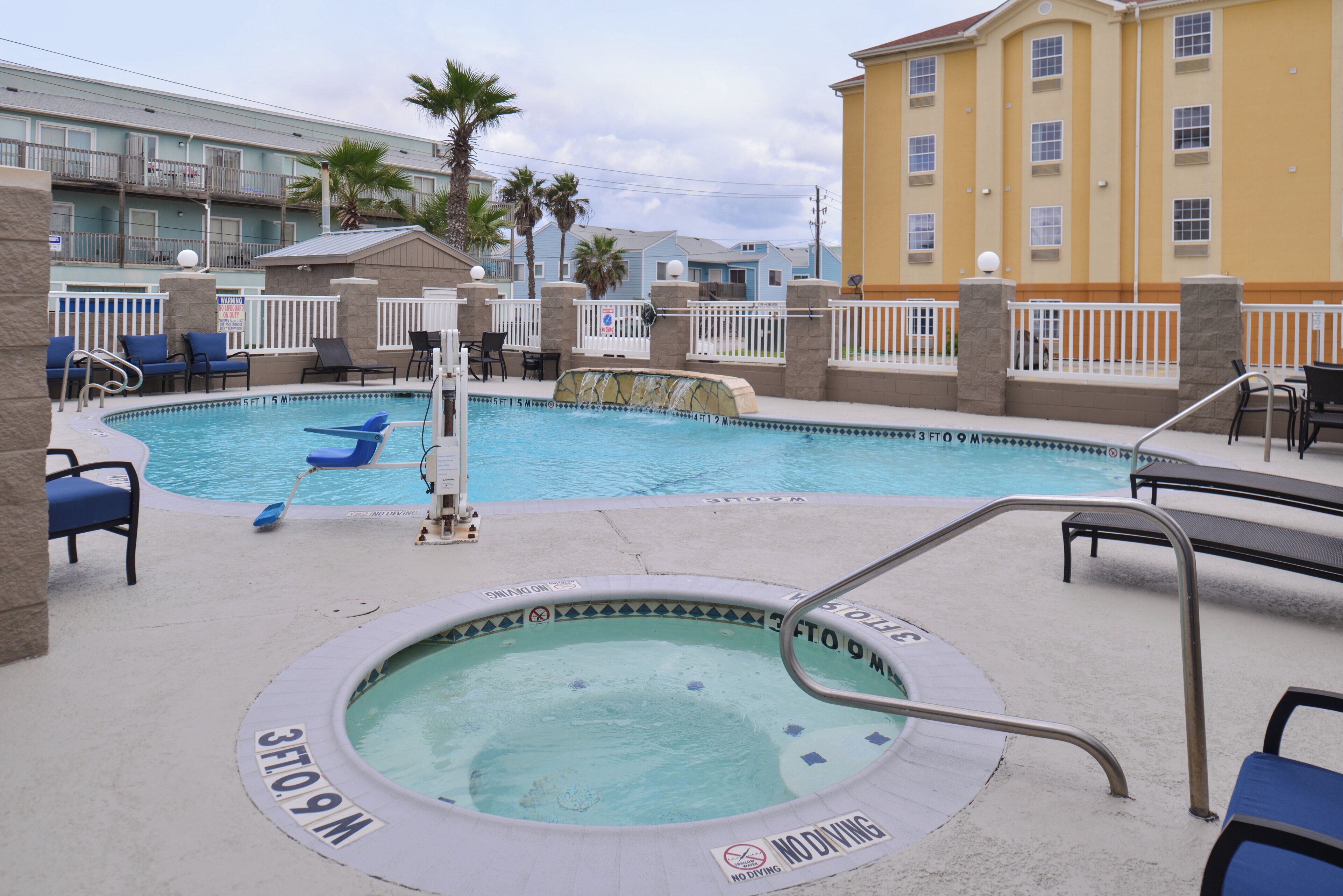A pool area with a hot tub, lounge chairs, and a no diving sign.