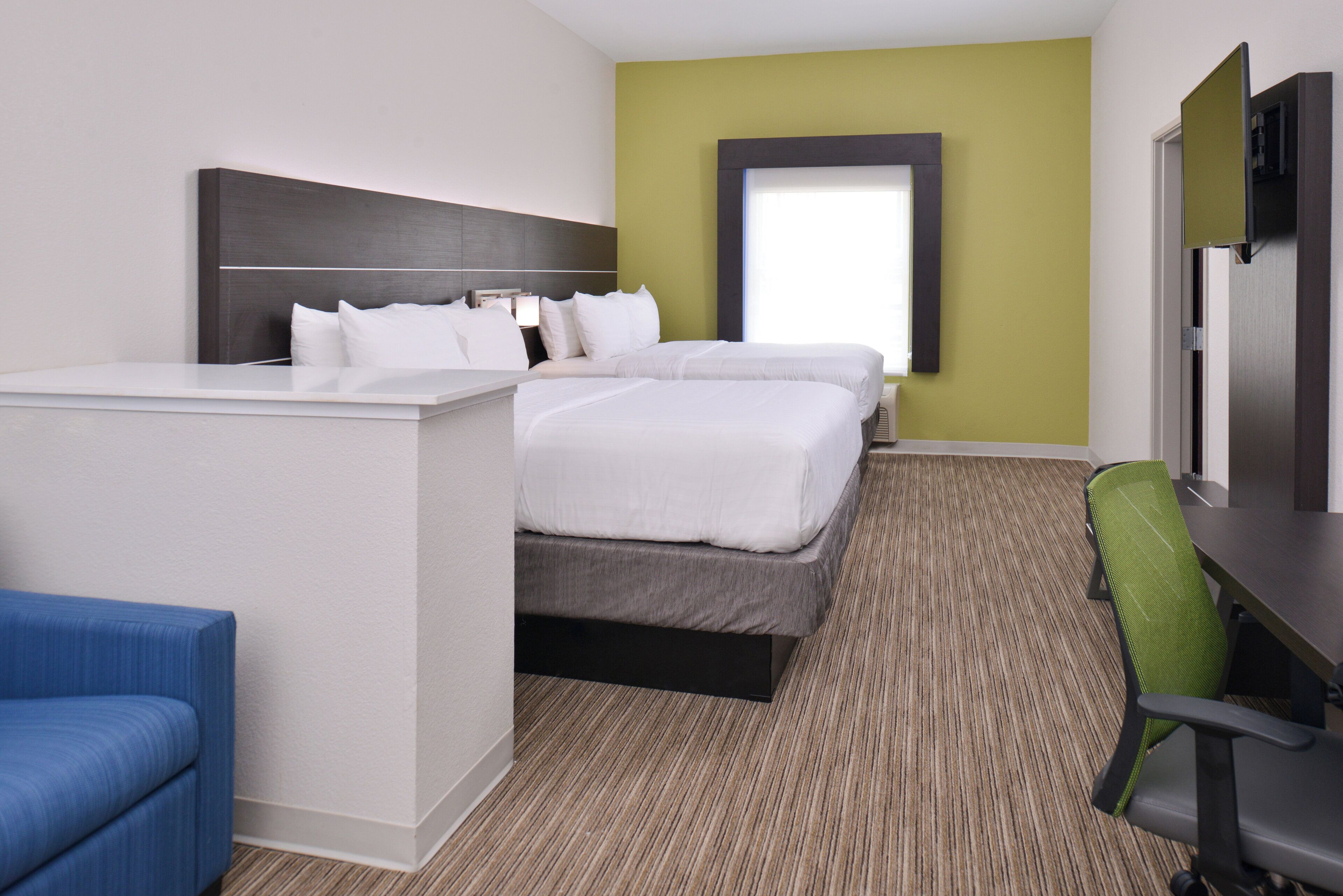 A hotel room with a bed, a desk, a chair, and a television.