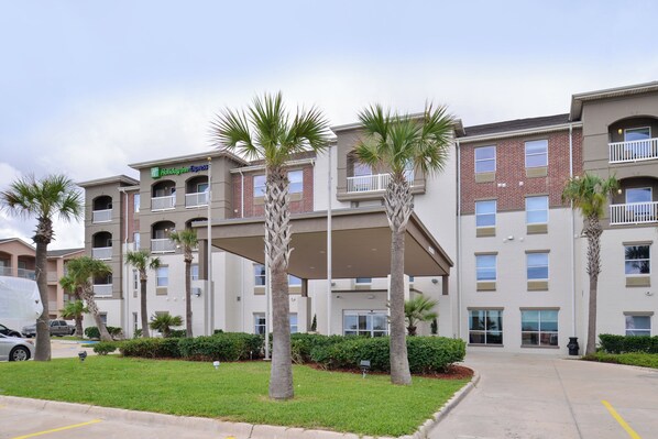 A multi-story hotel with a central atrium, palm trees, and a parking lot. - Holiday Inn Express & Suites Corpus Christi - N Padre Island by IHG (Corpus Christi)