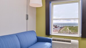 Une pièce avec un canapé bleu, une fenêtre donnant sur la plage et un climatiseur fixé au mur.