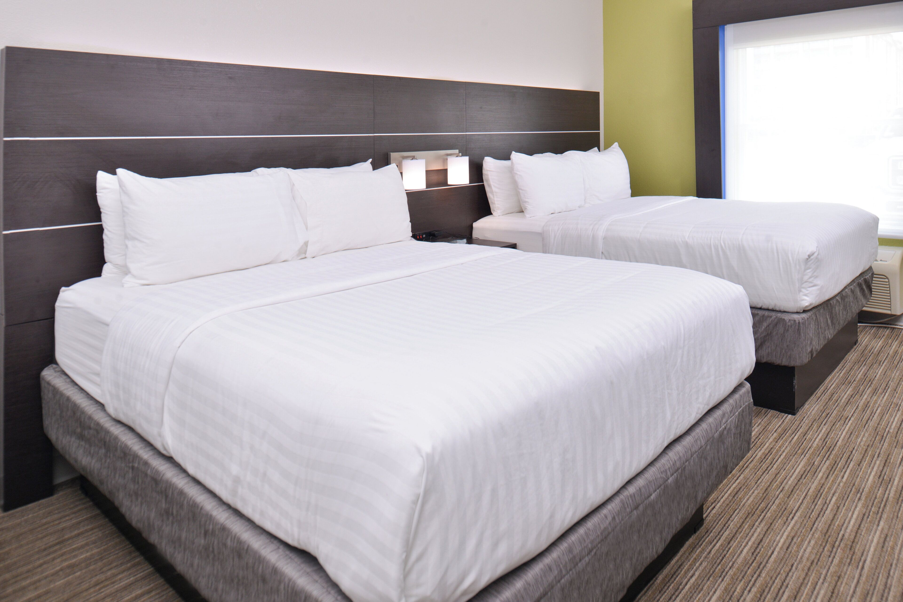 Ein Hotelzimmer mit zwei Betten, einem Kopfteil und einem Nachttisch mit Lampe.