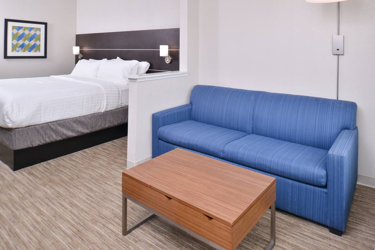 Ein Hotelzimmer mit einem Bett, einem blauen Sofa und einem Holztisch.