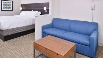 Una habitación de hotel con una cama, un sofá azul y una mesa de madera.