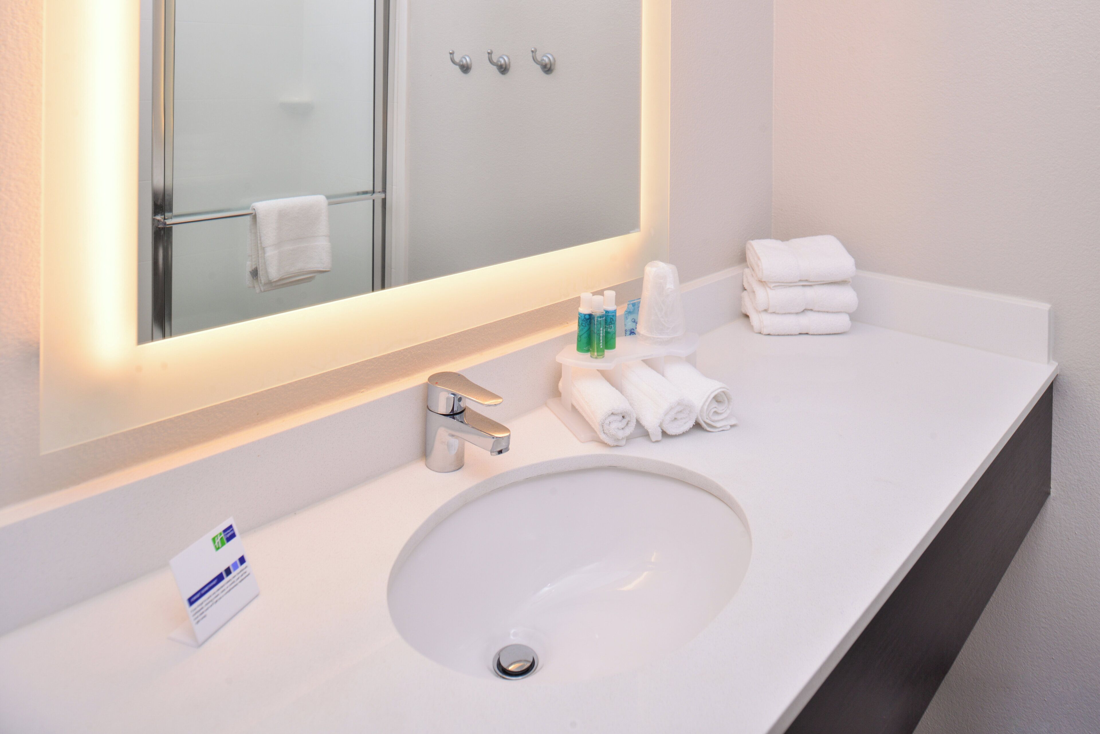 Une salle de bain avec un lavabo blanc, un miroir et un porte-serviettes.