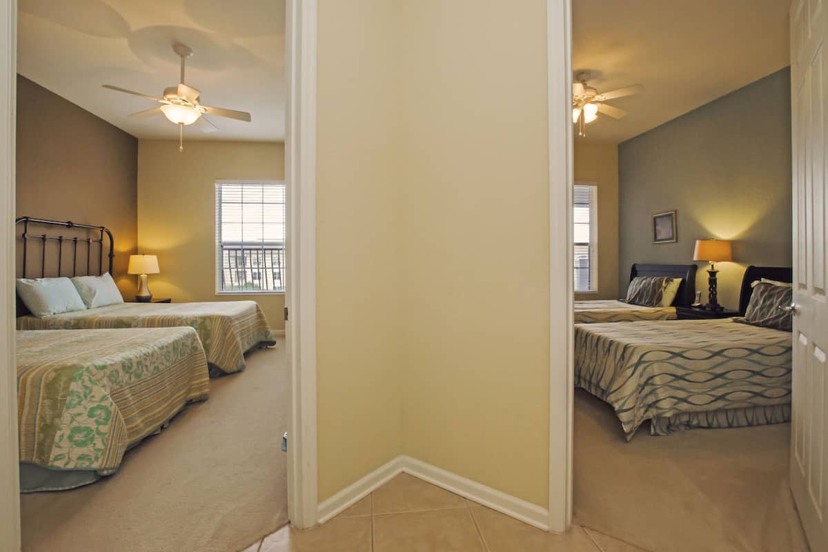 A bedroom with two beds, a ceiling fan, and a window.