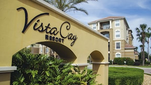 A sign for Vista Cay Resort with a clear archway and lush greenery.