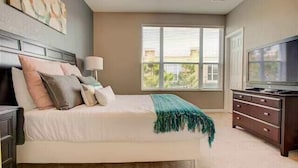 A bedroom with a bed, a dresser, a TV, and a window with blinds.