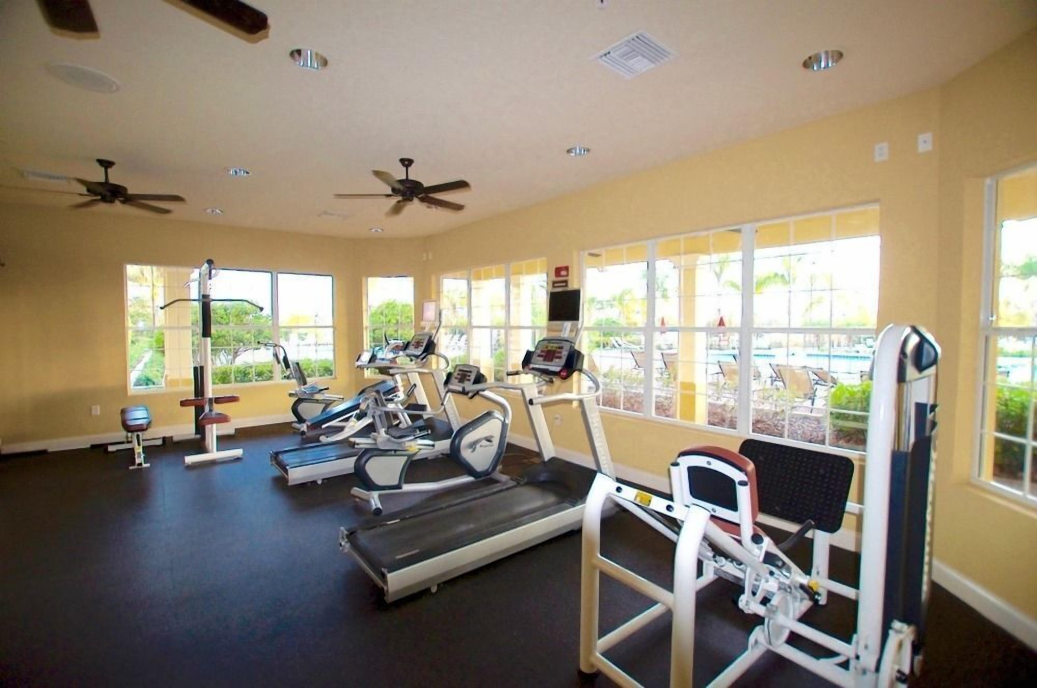 Un gimnasio con cintas de correr, elípticas y equipo de pesas.