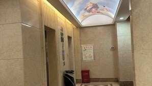 A hotel lobby with a tiled floor, a ceiling mural, and a trash bin. - Vienna International Hotel (Changzhou Hutang) (Changzhou)