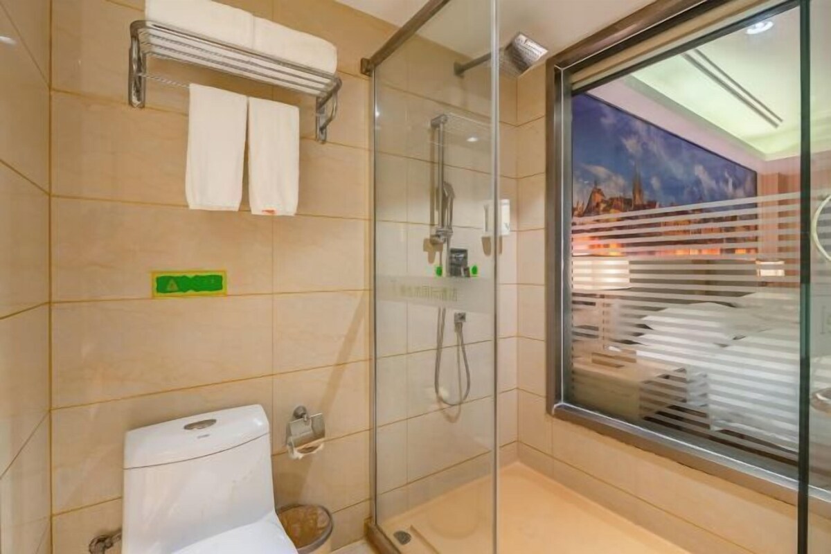 A modern bathroom with a glass shower enclosure, a toilet, and a towel rack.