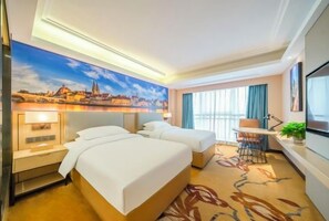 A hotel room with two beds, a desk, a chair, a large window with curtains, and a cityscape painting on the wall. - Vienna International Hotel (Changzhou Hutang) (Changzhou)