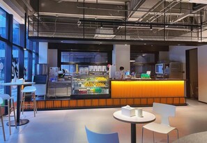 A modern cafe interior with a counter, seating area, and a refrigerated display case.