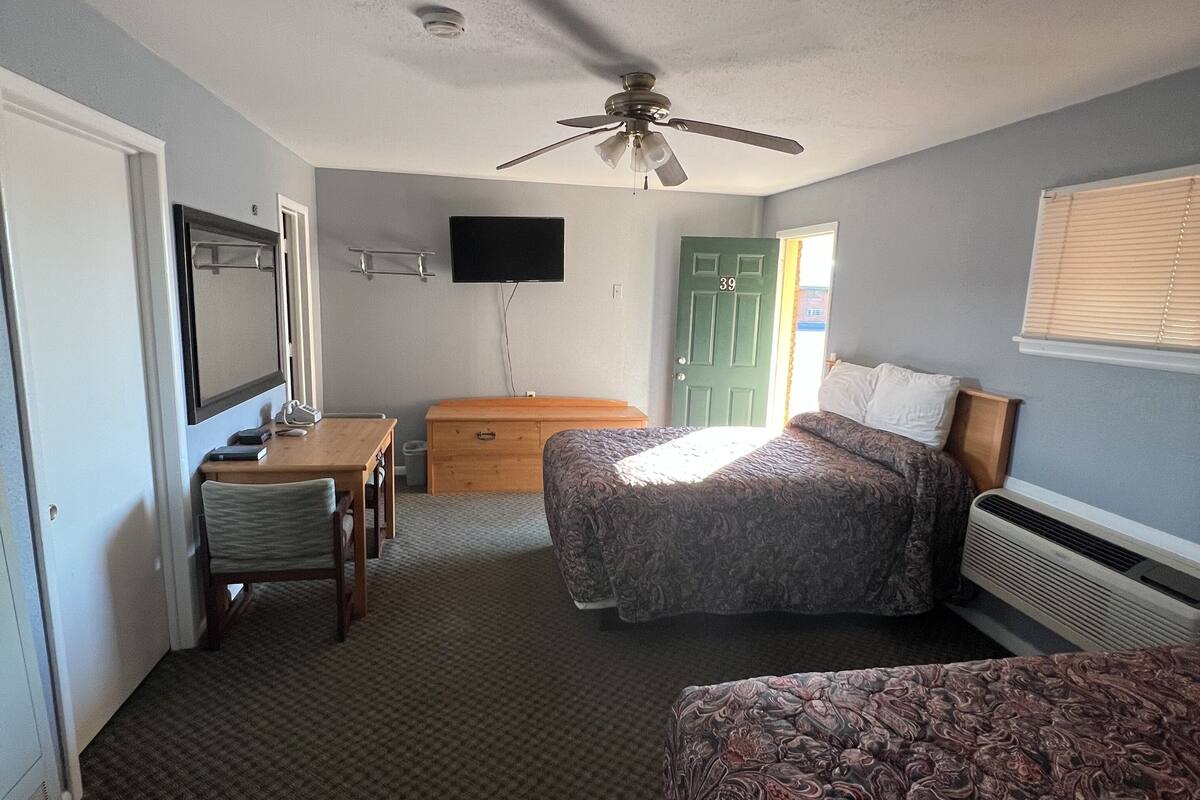 Ein Schlafzimmer mit einem Bett, einem Schreibtisch, einem Stuhl, einem Fernseher und einer Tür.
