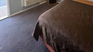 A hotel room with a bed, a television, a heater, and a window with curtains.