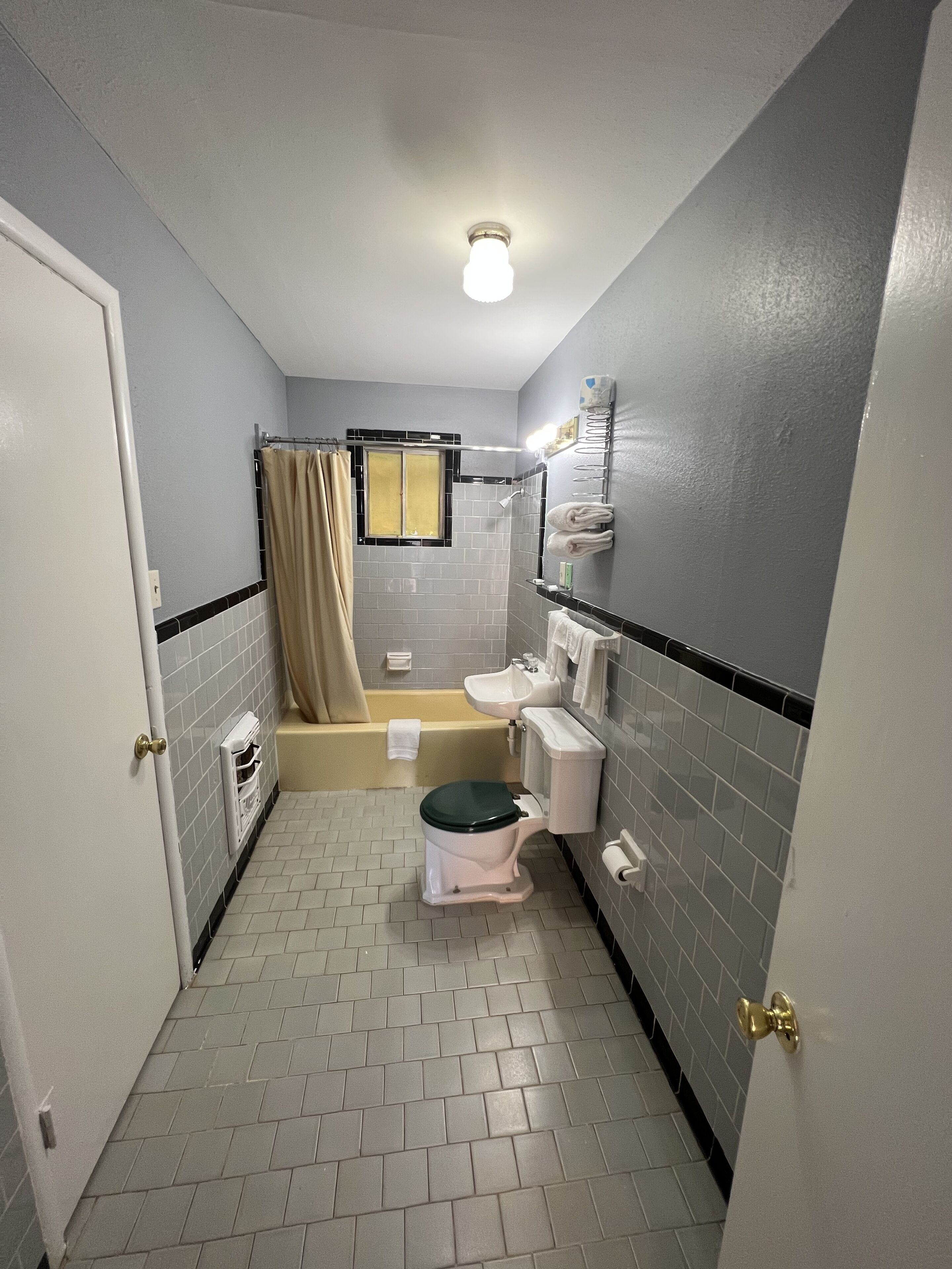 A small, narrow bathroom with a toilet, sink, and bathtub.
