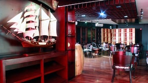 Un interior de restaurante con mobiliario de madera, un modelo de barco y una zona de bar.
