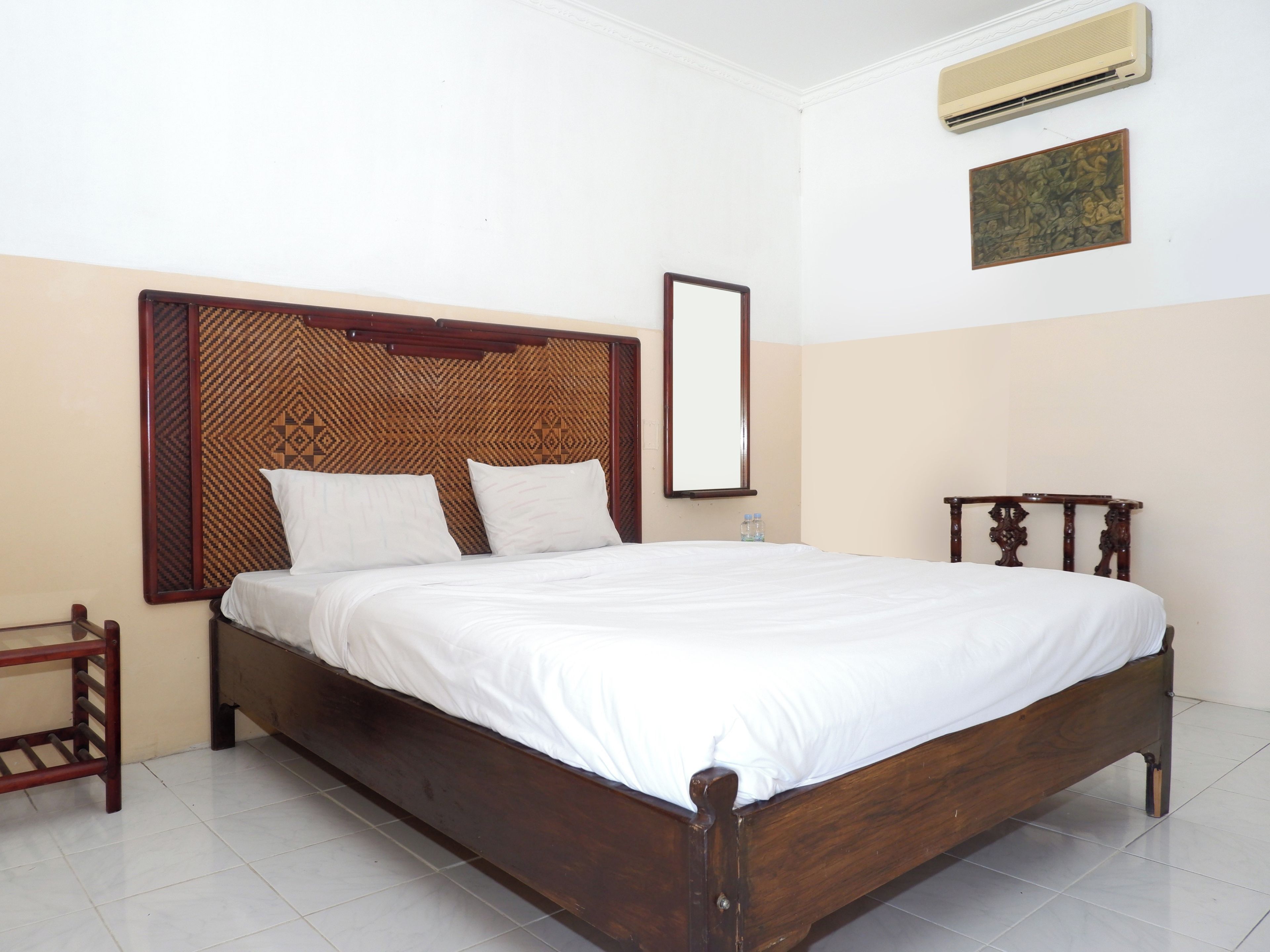 A neatly made bed with a wooden headboard and a single bedside table.