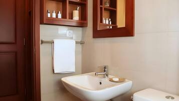 A bathroom with a white sink, a toilet, and wooden cabinets above the sink.