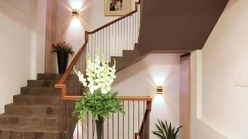 A staircase with a wooden handrail, a potted plant, and a wall-mounted light fixture.