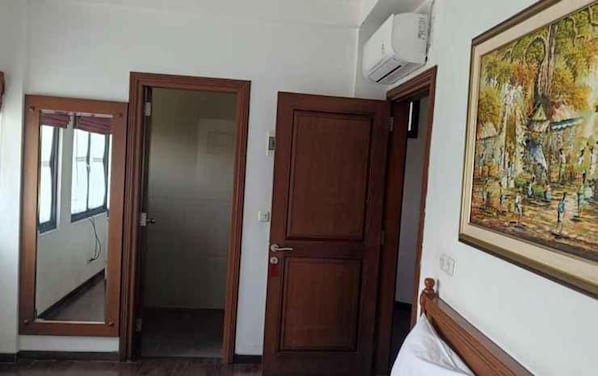 A room with a bed, a door, and a painting on the wall.